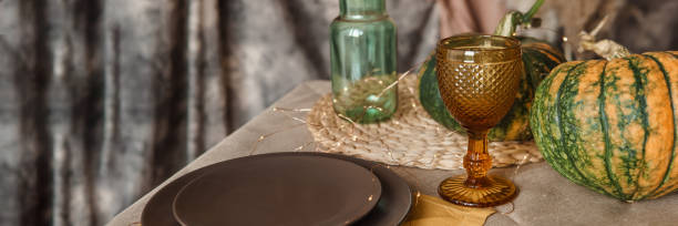 istock Autumn interior: a table covered with dishes, pumpkins, a relaxed composition of Japanese pampas grass. Interior in the photo Studio. Close - up of a decorated autumn table. 1735337098