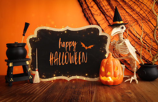 holidays image of Halloween. pumpkin and bird skeleton over wooden table