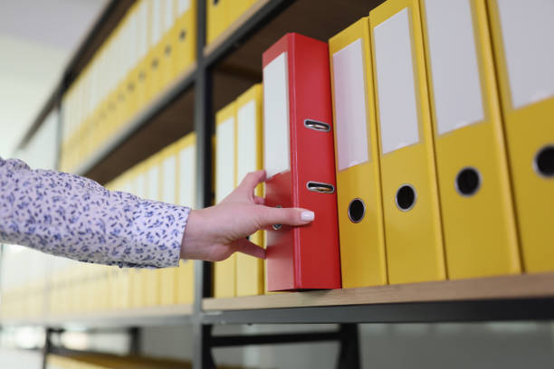 istock Hand of woman taking red ring binder from office archive 1735357513