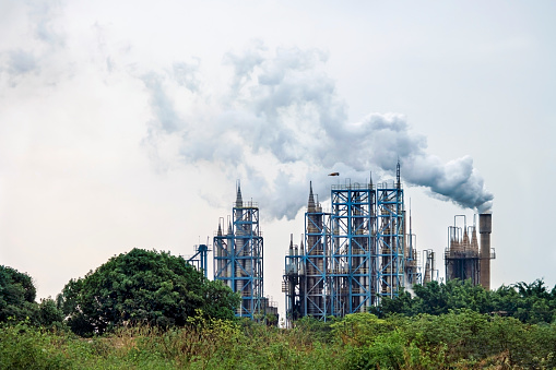 Photo of chimneys of a industrial plant emitting gases in the air.