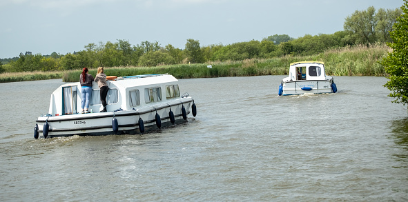 Two holiday cruisers motoring along the River Bure, Norfolk Broads