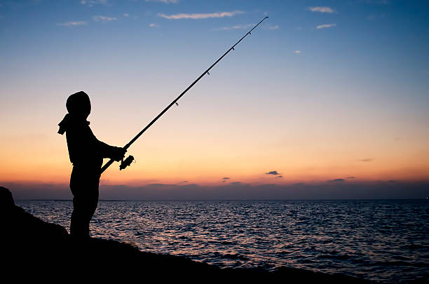istock Man fishing silhouette at sunset on a seashore 173538842