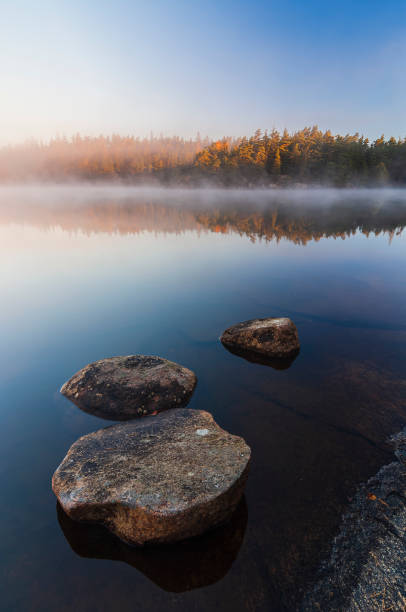 istock Still lake with boulders at sunrise 1735395823