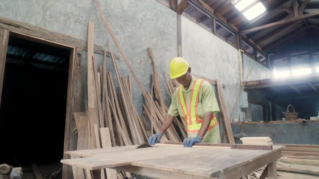 Asian carpenter machine to cut of wood in workshop.