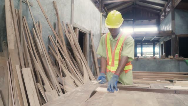 Asian carpenter machine to cut of wood in workshop.