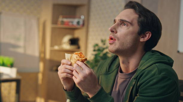 istock Closeup man having pizza lunch break at office. Talking relaxed guy eating food 1735401960