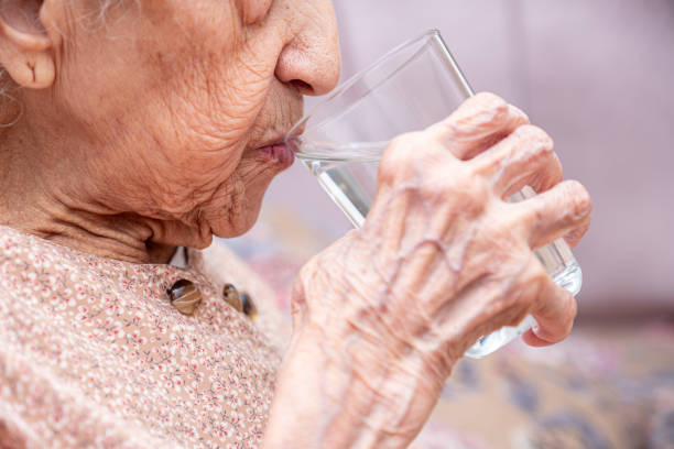 istock Old woman drinking water from glass cup 1735403288