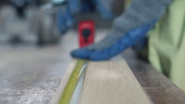 Close up hand carpenter measuring piece of wood in workshop.