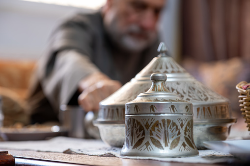 Arabian ornate tin  on living room table with arabic old man in the background