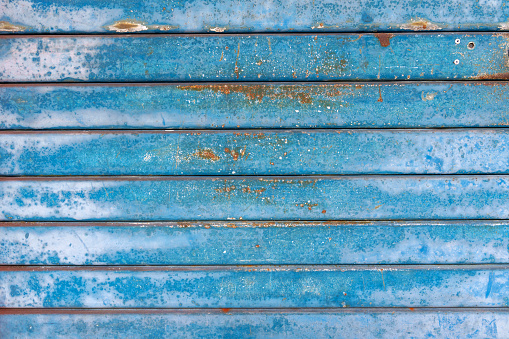An old rolling metal door background, painted in blue and displaying patinated metal