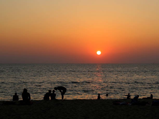 istock Sunset over Karon Beach and People Silhouettes 1735404014
