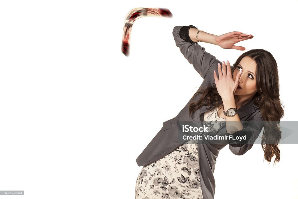 Woman shielding herself from flying boomerang frightened woman defending herself with her hands from the boomerang which she threw to someone else Boomerang Stock Photo