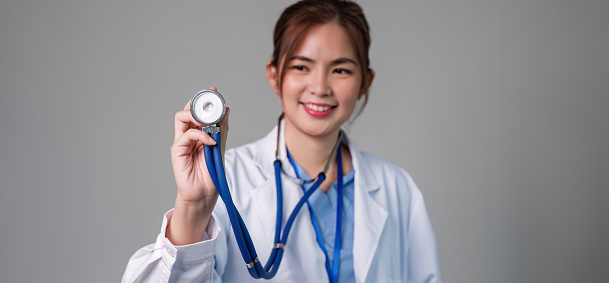 Portrait of female doctor using stethoscope on flat background. health care concept Female doctor using equipment to check patient's health.