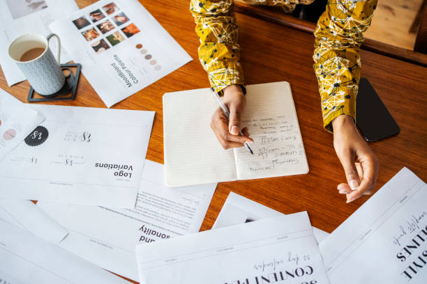 Female designer working on new creative project making notes in a book on office desk