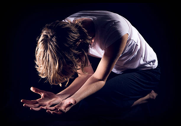 mulher ajoelhada em oração isolado no preto - kneeling praying women begging - fotografias e filmes do acervo