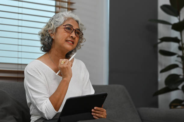 istock Portrait image of an Old Asian woman using a digital tablet while sitting on the sofa 1735416320