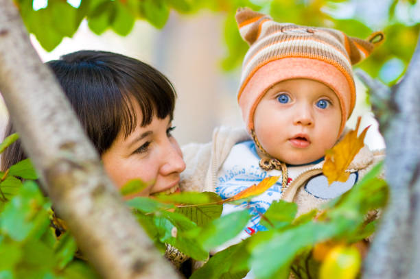 Mother holding baby in park stock photo