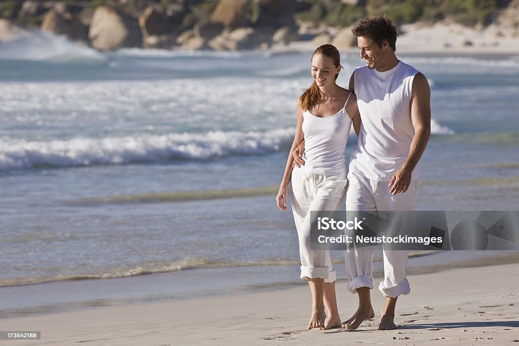 Romantic young couple walking together on beach Full length of smiling romantic young couple walking together on beach Beautiful People Stock Photo