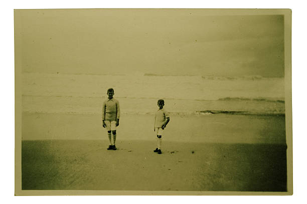Stranded Antique photo of two little boys standing on a beach yt stock pictures, royalty-free photos & images