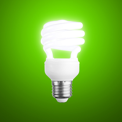 An energy efficient compact fluorescent lightbulb on a green background. Includes accurate clipping path.