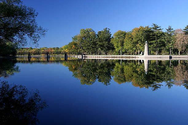 summer day time park landscape walking district area waterfront fence by marble palisade along river stream, green trees foliage and blue sky background scenic view