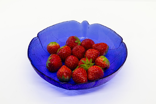 Strawberries in blue bowl isolated on white