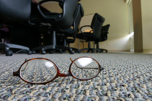 a businessman's glasses on the floor of an office