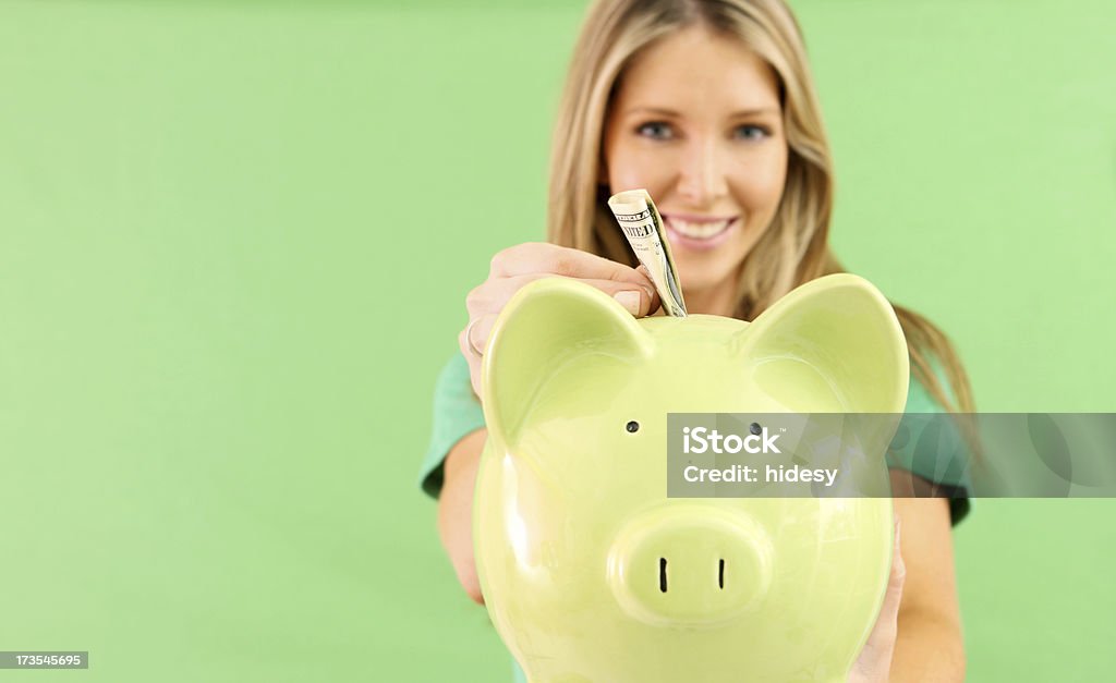 Green Money Piggybank with woman putting in money 20-24 Years Stock Photo