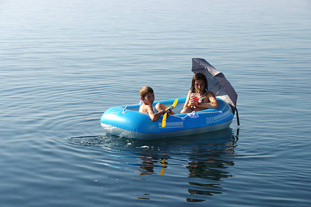 Brother and sister having fun in a boat in the midle of the sea.
