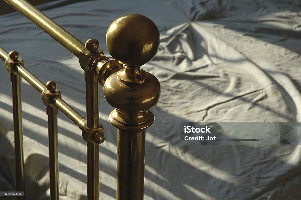 Interior - Brass bedstead "Antique brass bed rail, evening light" Bed Frame Stock Photo