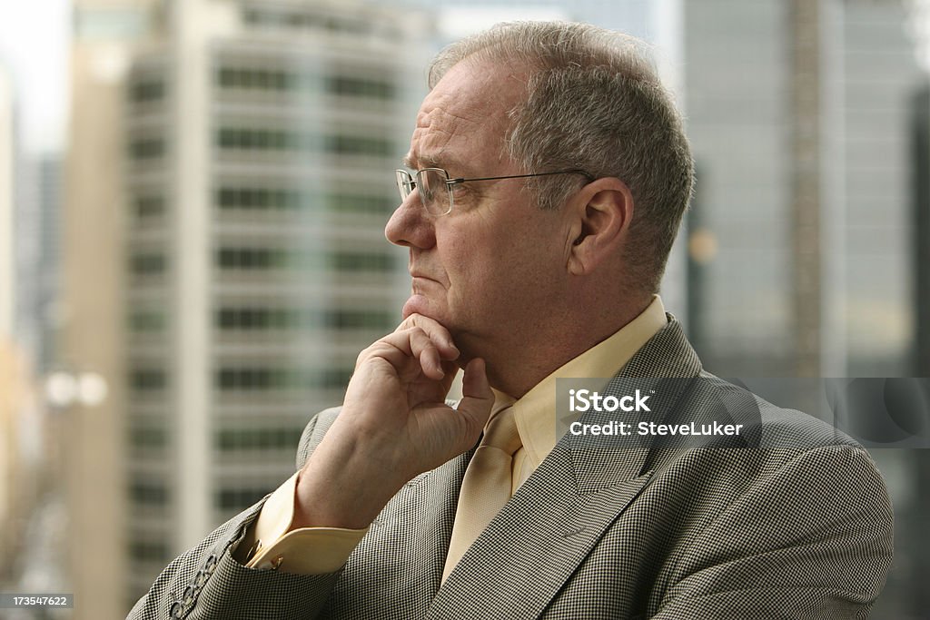 Businessman thinking. A mature businessman thinking. Office buildings behind. Men Stock Photo