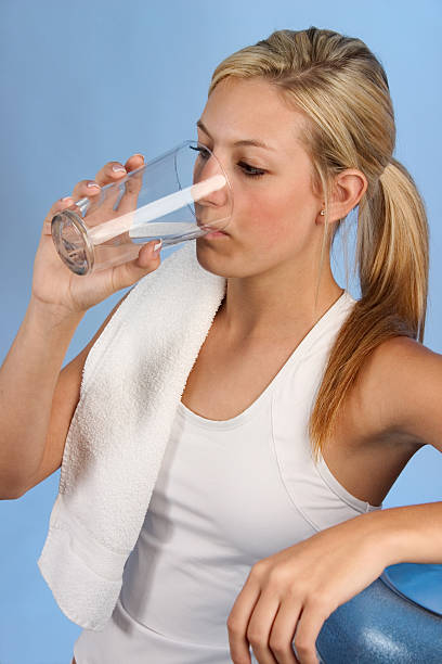 Woman Drinking Woman drinking water from a water cooler after a workout. fit girl drinking mineral water stock pictures, royalty-free photos & images