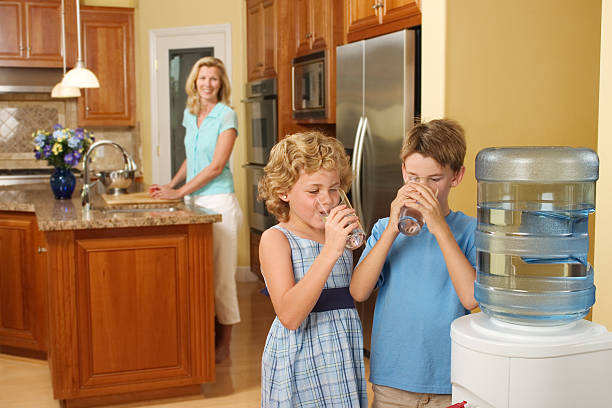 Children Drinking Purified Water Children at home drinking purified water from a water cooler. water cooler stock pictures, royalty-free photos & images