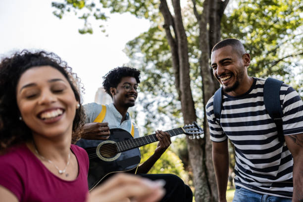 istock Student friends singing and playing guitar at university campus outdoors 1735488855