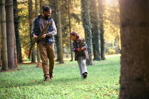 istock Black father and daughter collecting twigs while camping in nature. 1735489929
