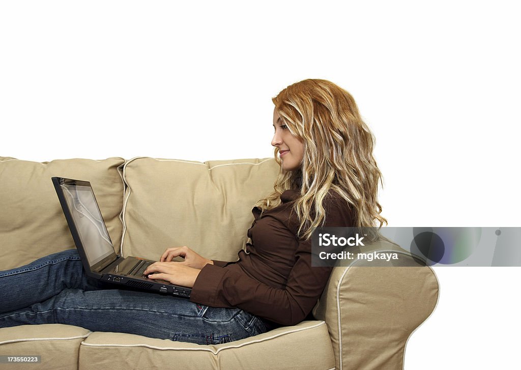 Ragazza utilizzando un computer portatile su un divano - Foto stock royalty-free di Lavoro a domicilio