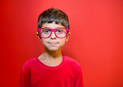 Boy in red pajamas, red glasses and red studio background for a glasses advertisement