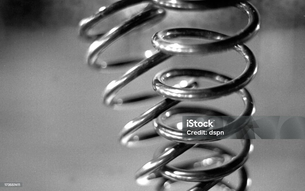 Silver spring being sprung on ground Shock absorber coil springs. Abstract Stock Photo