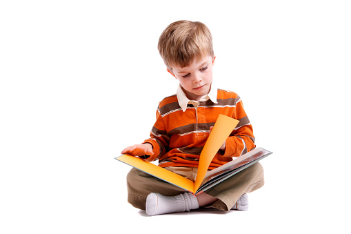 Little boy reading a book on a white background