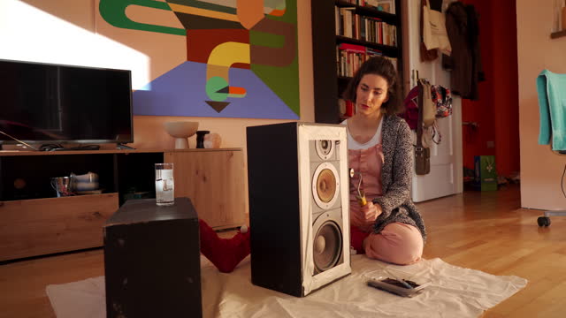 Adult woman renovating old speakers in living room