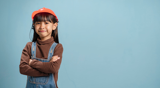 A little girl is wearing a engineer hat, is happy to learn.