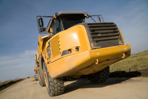 Yellow dump truck sitting idle at a construction site on a warm summer day.