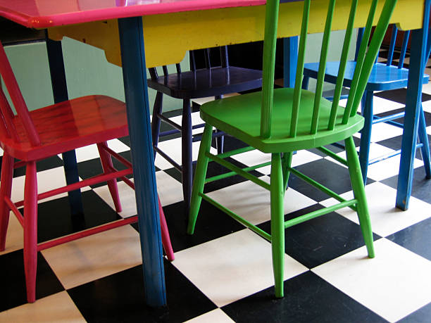 colored chairs and table on b&w tile floor stock photo