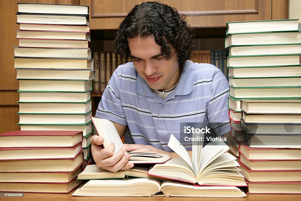 At the library A reading young man at the library surrounded by lots of books. Adult Stock Photo