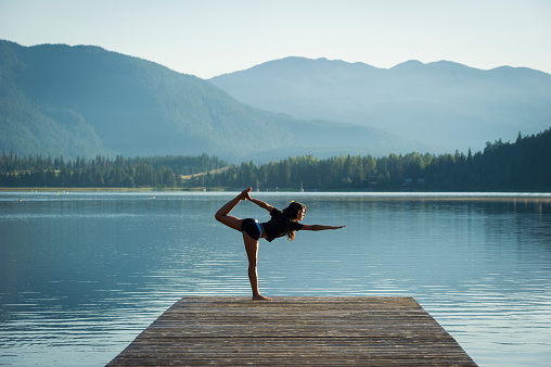 Woman doing sunrise yoga on Alta Lake in Whistler, Canada. Yoga and wellness themes.