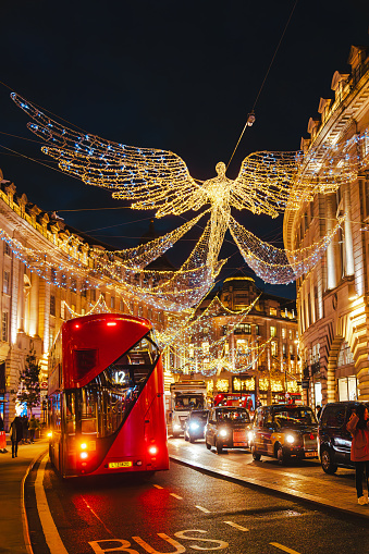 View of a colourful decorated festive Christmas decoration and holiday lights at night and double decker red bus on road in Regent Street in Central London, England, UK