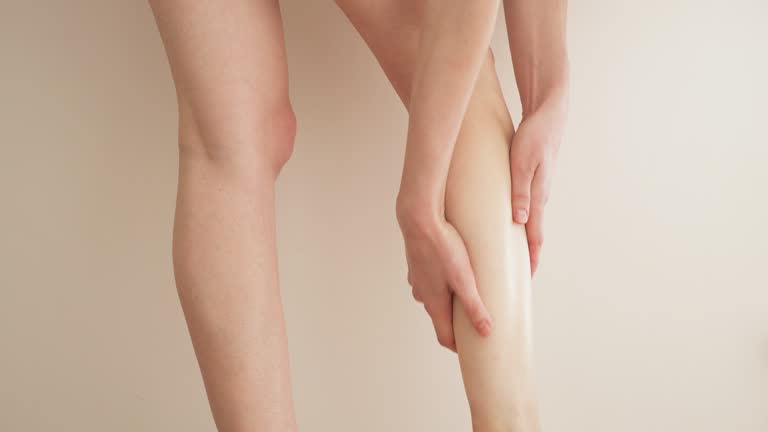 Europe woman massages her thin and long tired legs at home. Prevention of varicose veins.