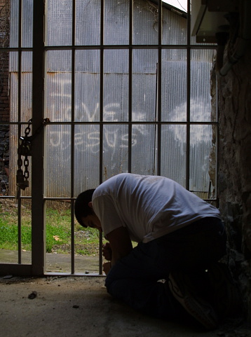 This is a picture of a friend praying with the words I love Jesus spray painted in the background.  The shot was taken with my Canon D30 digital camera while on a tripod for support.