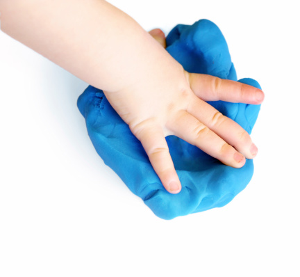 Young child playing with blue play dough.