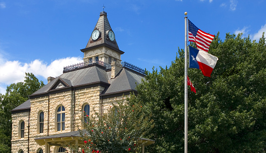 View of the Glen Rose, Texas Townsquare, Somerville County Courthouse in the background, US and Texas flags in foreground